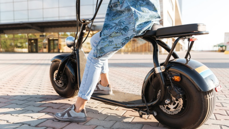Cropped image of a woman sitting on a motor bicycle outdoors