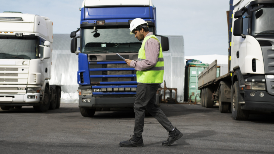 full-shot-man-walking-by-trucks-fleet